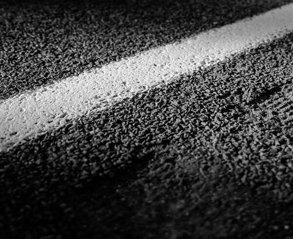 close up of concrete road with white solid lines, black and white