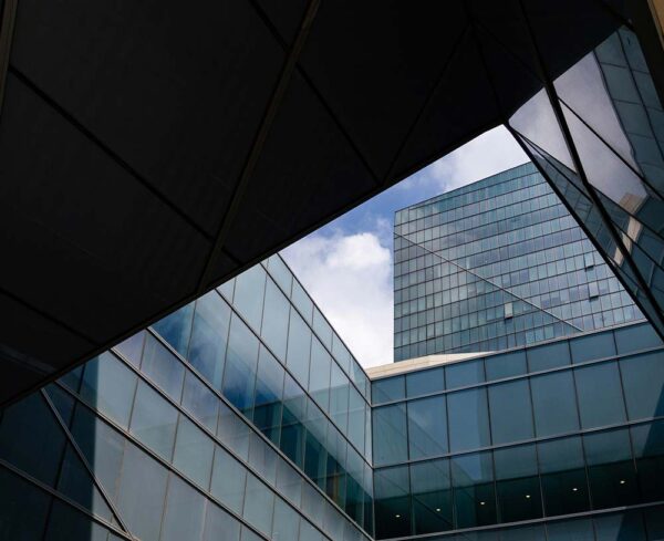 obstructed view of office buildings with blue windows and blue cloudy sky