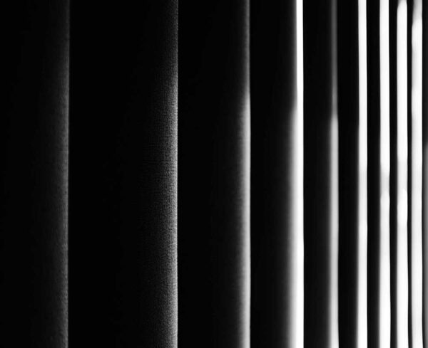black and white image that looks almost like folder curtains going into a more lit area