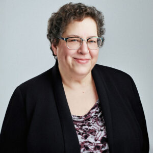 Ellen Brickman looking into the camera slightly smiling and slightly angled to the right with arms at the sides.