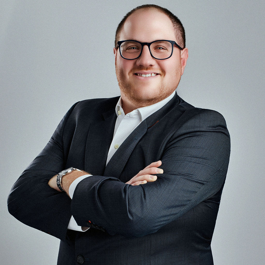 Jeffrey Dorfman looking into the camera angled to the left with arms crossed and smiling.