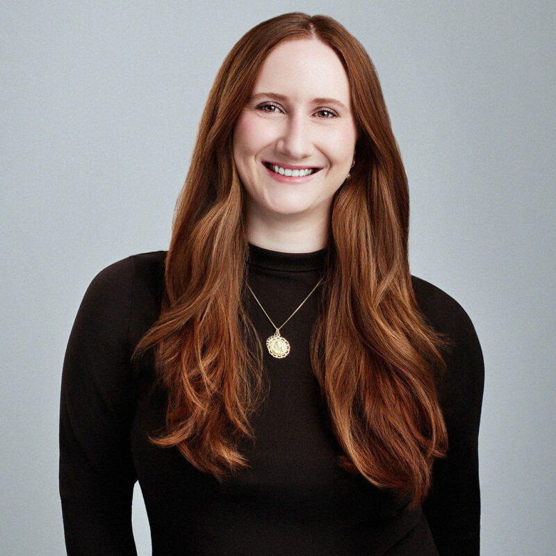 Leslie O'Neill looking straight into the camera smiling with arms at the sides.